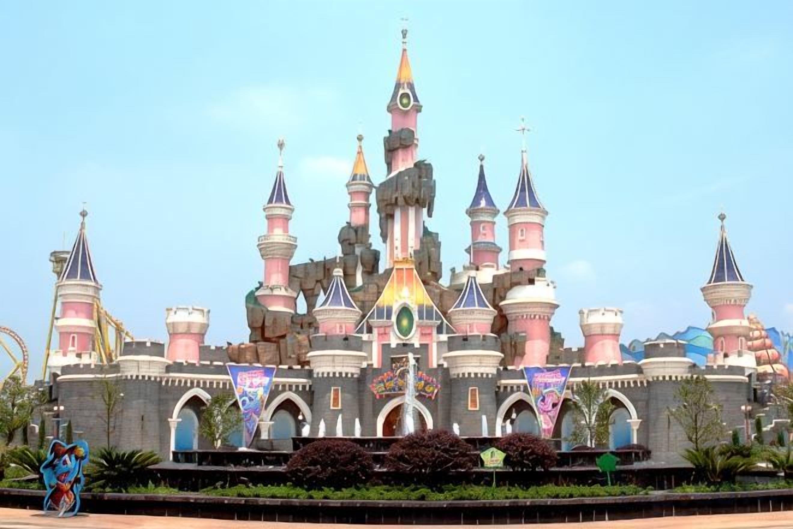 Una gran estructura que recuerda a un castillo, con múltiples torres y una torre central, rodeada por un jardín cuidado y senderos.