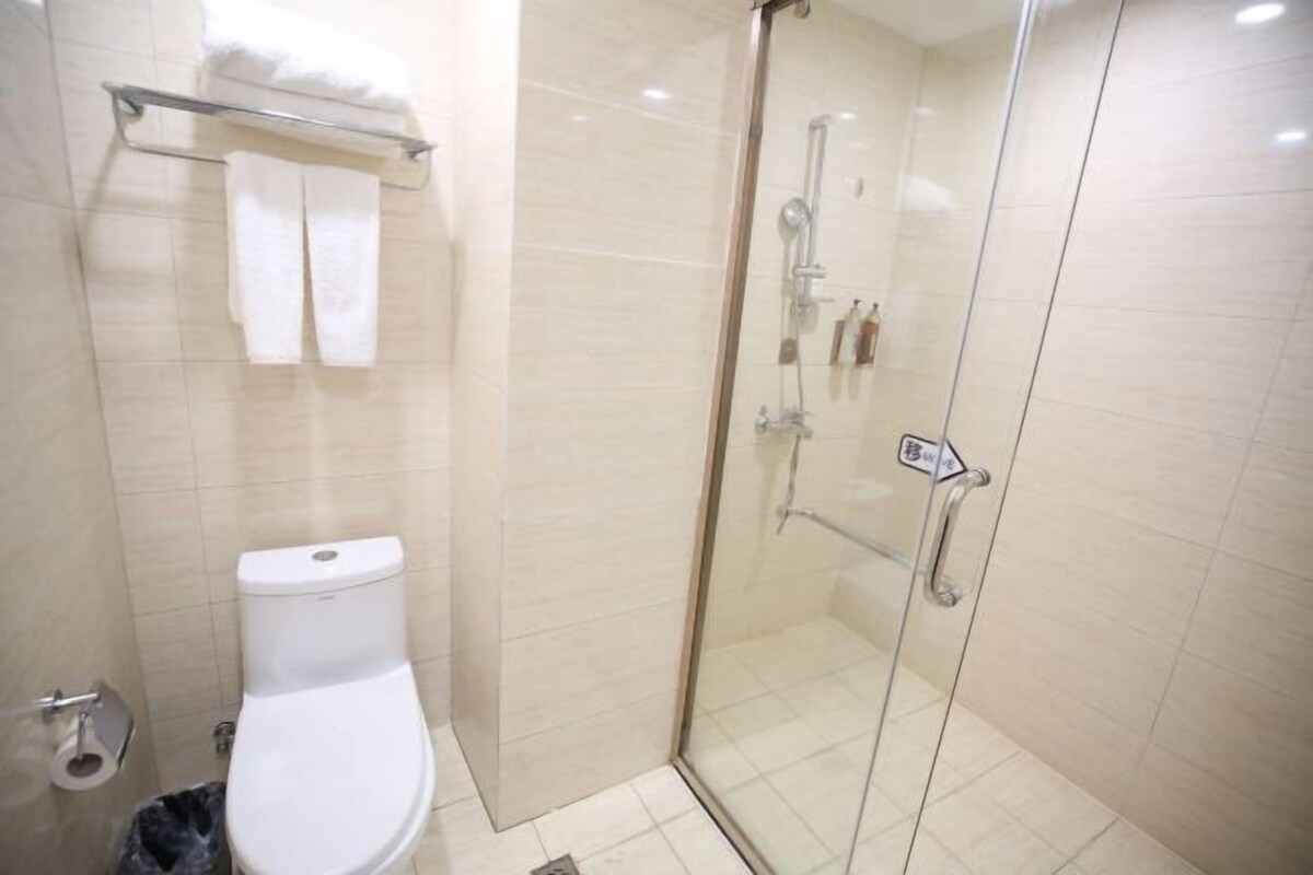 Ein modernes Badezimmer mit einer gläsernen Duschkabine, einer weißen Toilette und einem Handtuchhalter.