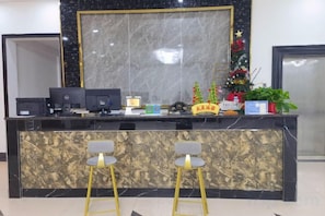 A reception desk with a computer, a small plant, and a decorative item. - Wenchang Ruyi Hotel (Wenchang)