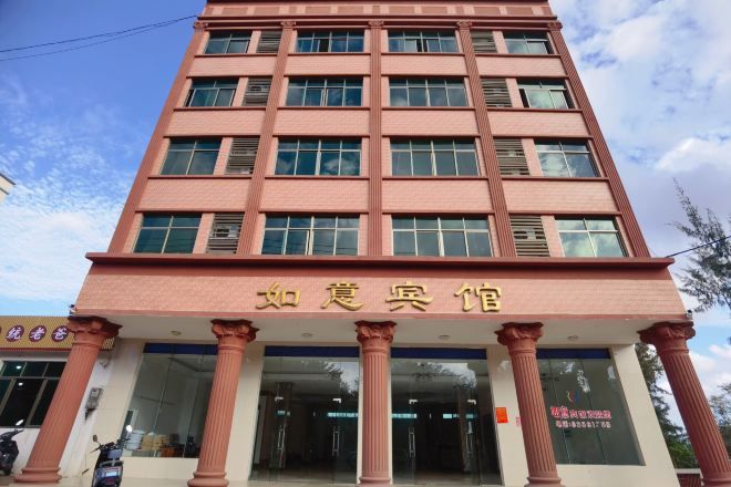 Um edifício com vários andares, com uma entrada imponente destacada por colunas grandes e uma placa em escrita estrangeira.