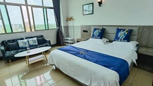 A hotel room with a large bed, a sofa, a small table, and a view of the outside. - Wenchang Ruyi Hotel (Wenchang)