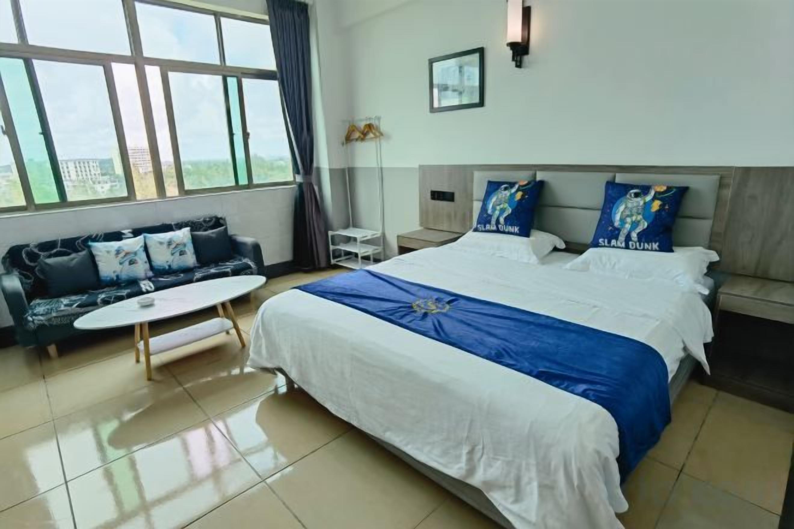 Habitación de hotel con una cama grande, un sofá, una mesita y vistas a la ciudad.