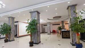 A spacious lobby with marble pillars, potted plants, and a reception desk. - Wenchang Ruyi Hotel (Wenchang)