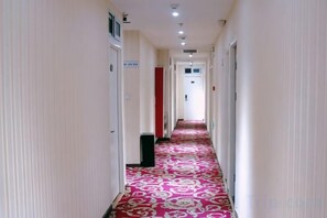 A hotel hallway with a patterned carpet, doors, and a trash bin. - jindaxiang Express Hotel (Baoji Jiangtan Road Store) (Baoji)