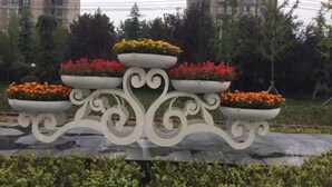 Una jardinera decorativa para exteriores con tres niveles, cada uno con flores de colores.