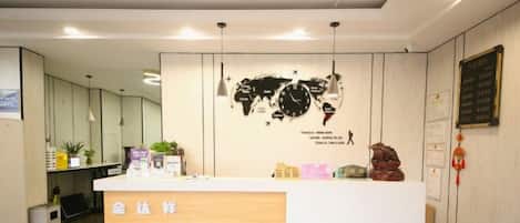 A reception desk with a world map and a clock on the wall, a plant, and a sign with Chinese characters.