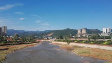 Un río con un puente, edificios y montañas al fondo.