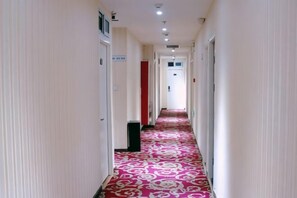 Un pasillo de hotel con alfombra estampada, puertas y un contenedor de basura.