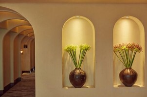 Dos jarrones con flores en nichos arqueados a lo largo de un pasillo.