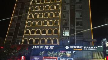 A multi-story building with illuminated windows and signage for various businesses, including a hotel and a restaurant.
