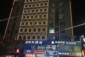 A multi-story building with illuminated windows and signage for various businesses, including a hotel and a restaurant.