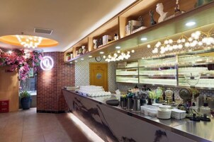 A restaurant interior with a counter, shelves with dishes, and a decorative ceiling light fixture.