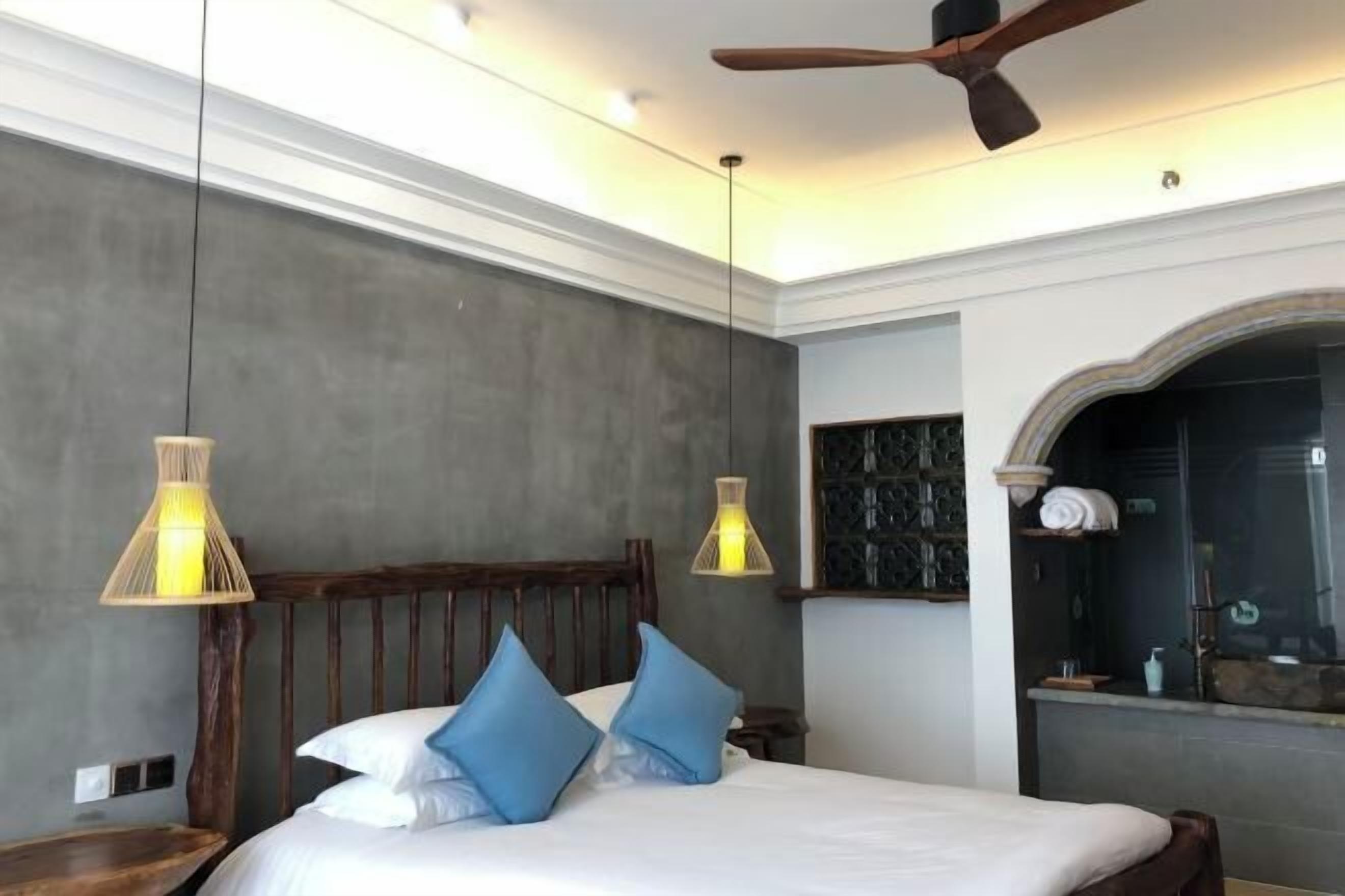 A bedroom with a wooden headboard, two bedside lamps, and a ceiling fan.