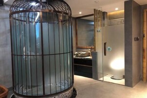 Un interior moderno con cerramiento de vidrio, baño privado con puerta de cristal y suelo de baldosas.