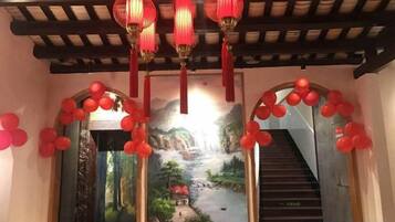 A staircase with red balloons and lanterns, leading to a room with a scenic mural.