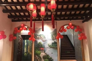 A staircase with red balloons and lanterns, leading to a room with a scenic mural.