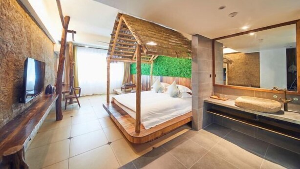 Una camera da letto moderna con un letto a baldacchino in legno, un muro in pietra, una parete verde, un grande specchio e una panca integrata.