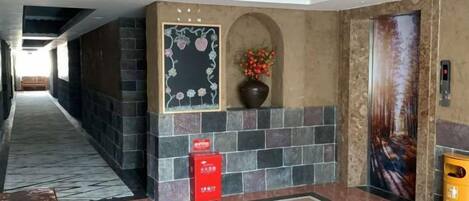 Eine Hotelhalle mit Marmorboden, einer Rezeption, einer wandmontierten Blumenvase und einer Tür mit einem Plakat.
