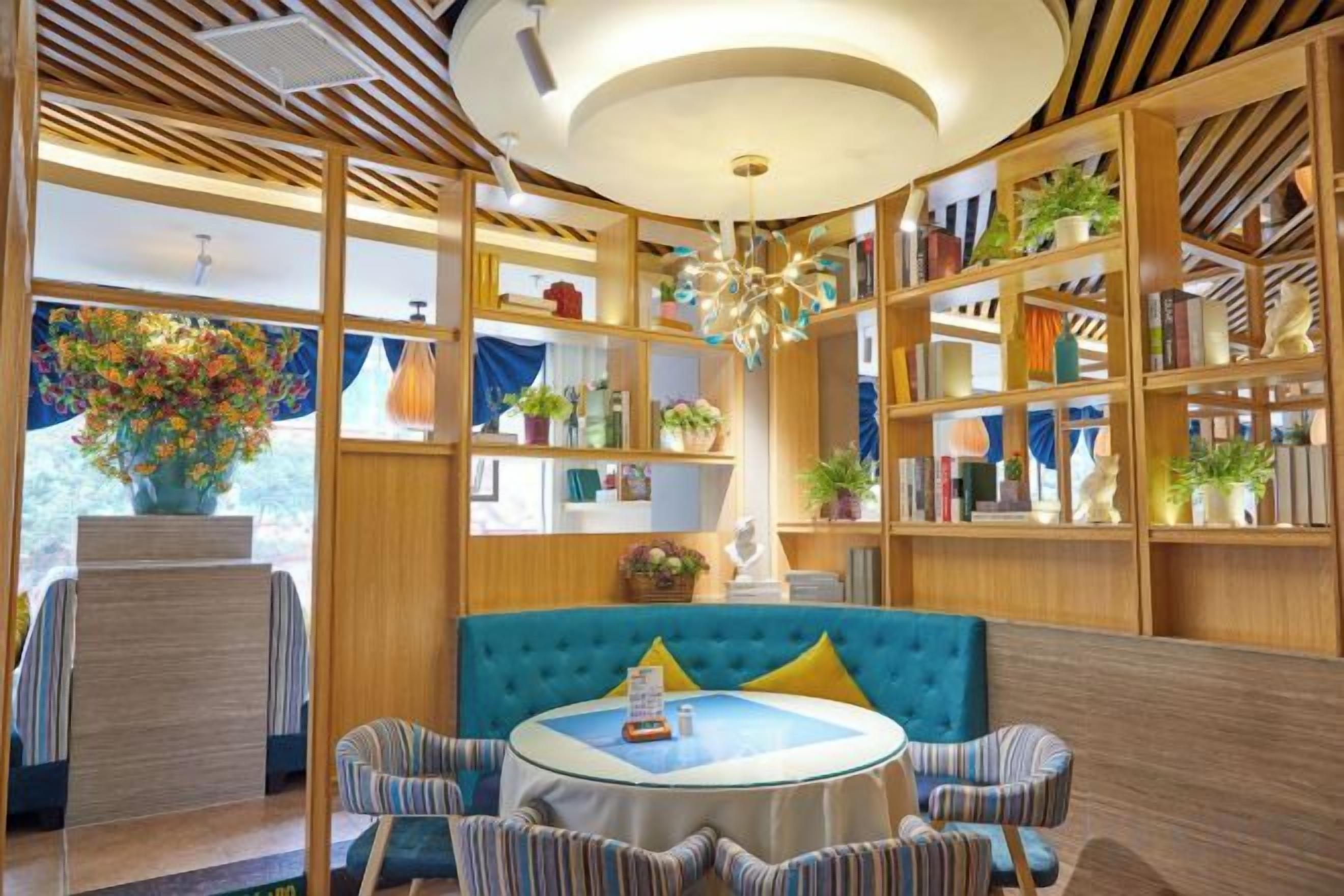 A room with a round table, striped chairs, a blue sofa, and a bookshelf filled with books and decorative items.