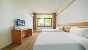 Habitación de hotel con una cama grande, un escritorio, un televisor y una ventana con cortinas.