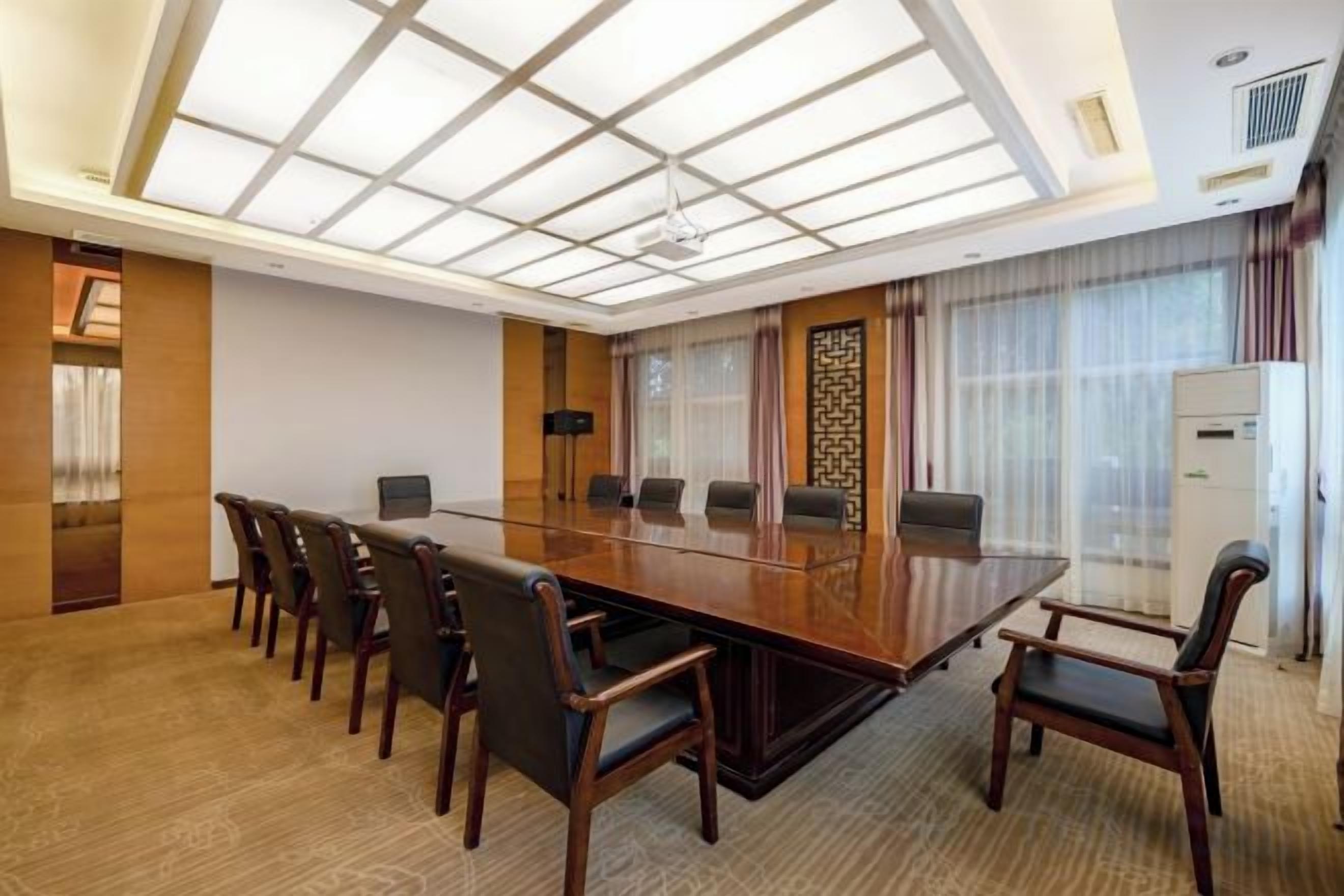 Ein Konferenzraum mit einem langen Tisch, Stühlen und einem modernen Deckenstil.