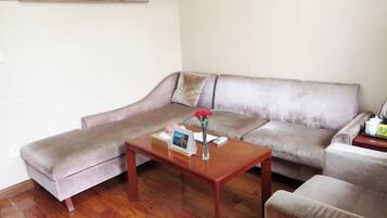 A living room with a grey sofa, a wooden coffee table, and a small table with a vase and picture frame.