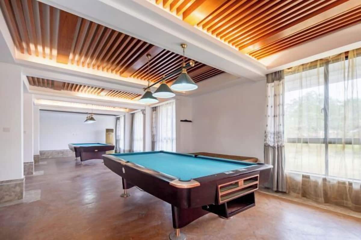 A pool table with a wooden ceiling and pendant lighting in a room with large windows.
