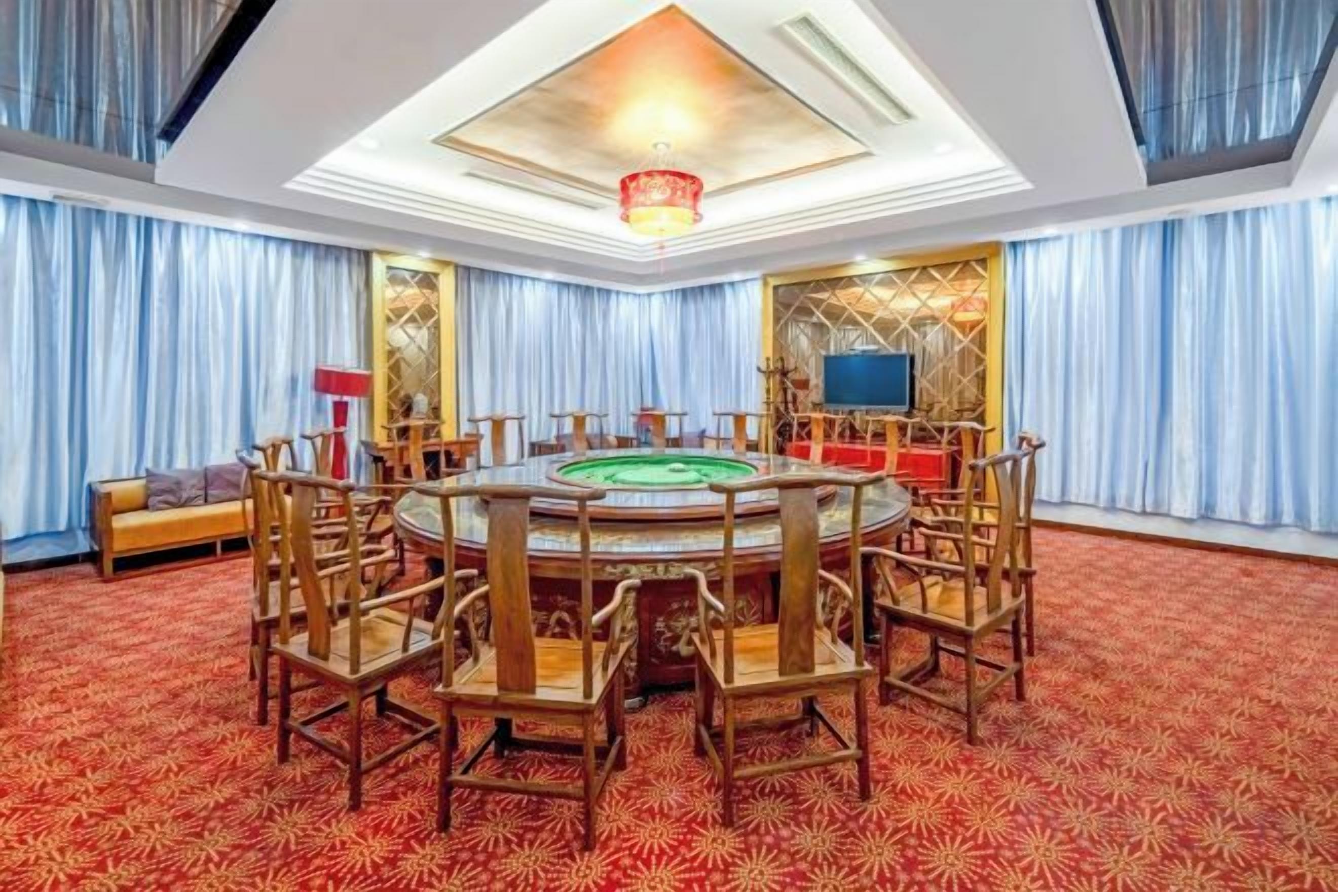 A circular room with a green pool table, wooden chairs, and a television on the wall.