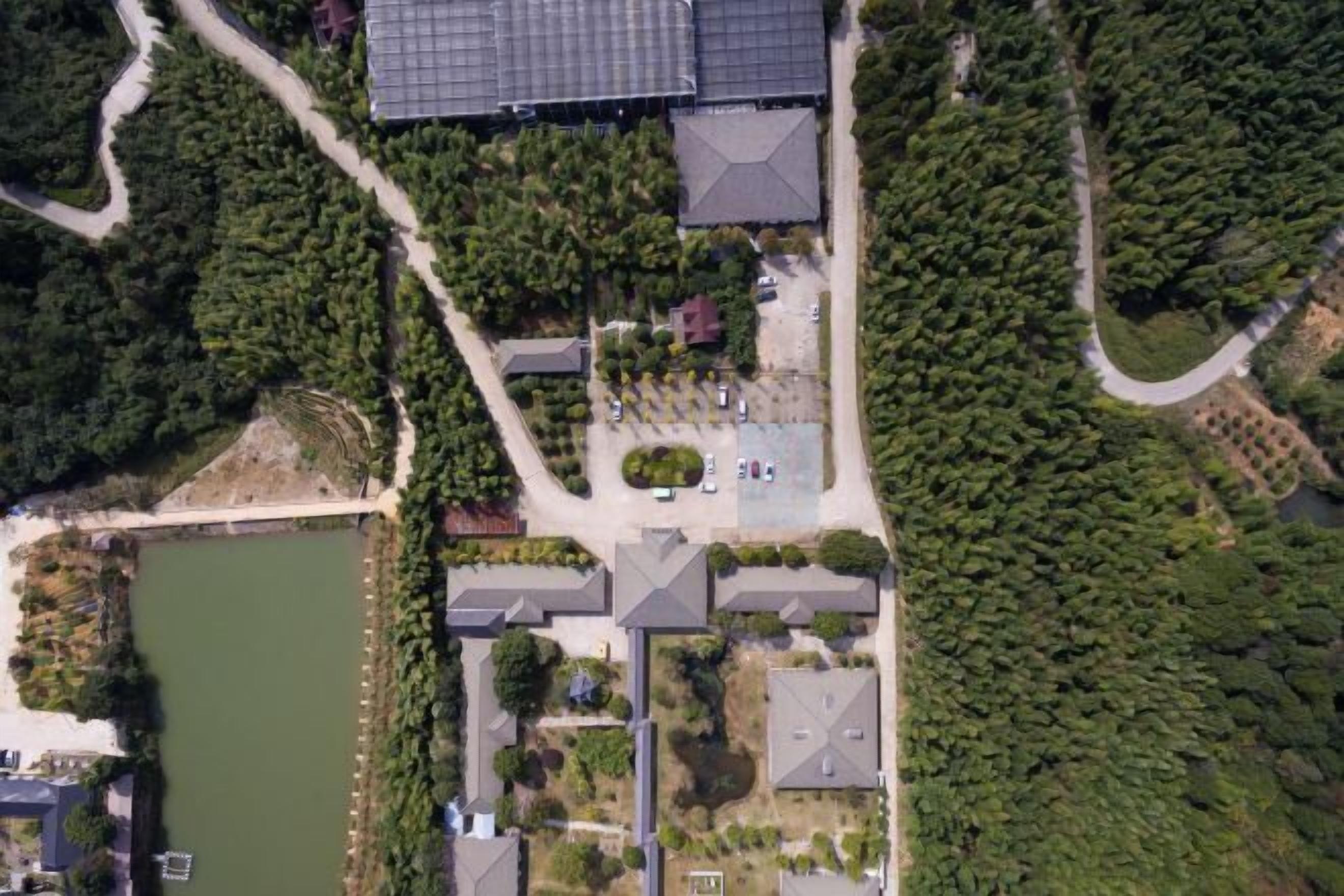 An aerial view of a residential area with houses, a lake, and a forested area.