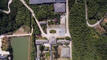 An aerial view of a residential area with houses, a lake, and a forested area.