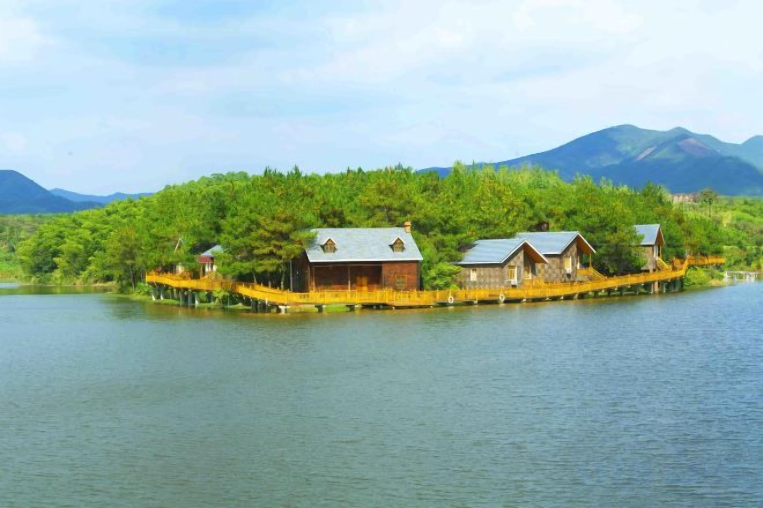 A lakeside property with multiple wooden cabins, a dock, and a forested hill in the background.