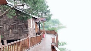 Una terraza de madera que lleva a una cabaña rústica con vista a un lago.