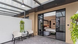 A modern room with a bed, a small table, two chairs, and a large window. - Tian Bo Hotel (Qianwei County)