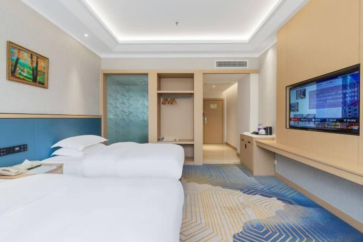 A hotel room with a bed, a desk, a television, and a bathroom.