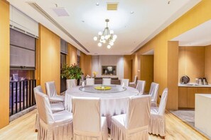 A modern dining room with a round table, white chairs, and a chandelier. - Tian Bo Hotel (Qianwei County)