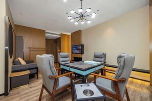 A hotel room with a dining table, four chairs, a television, and a sofa. - Tian Bo Hotel (Qianwei County)