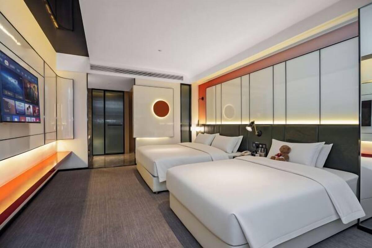 A hotel room with two beds, a TV, and a modern design.