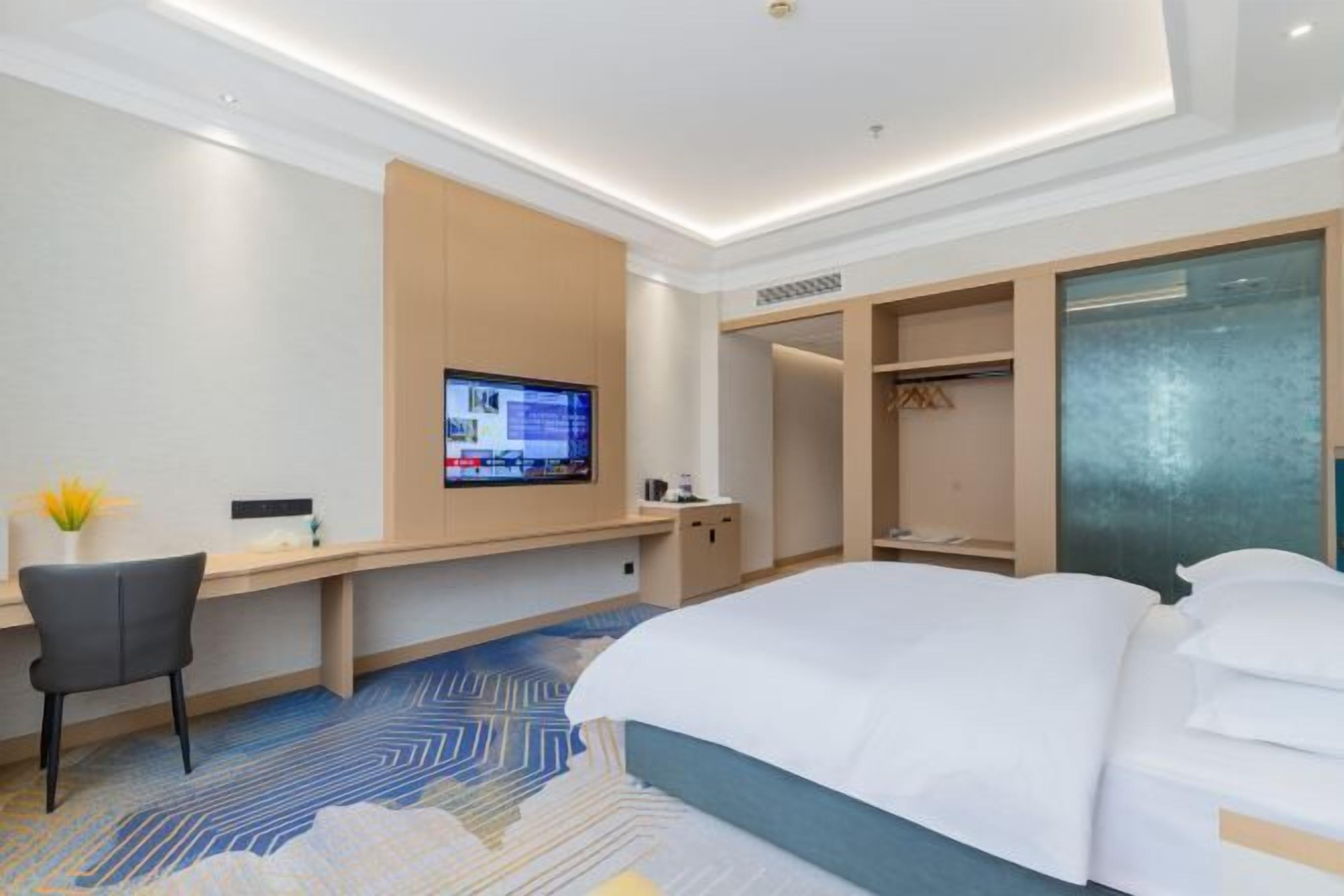 Ett hotellrum med en säng, ett skrivbord med en dator, en tv och en garderob.