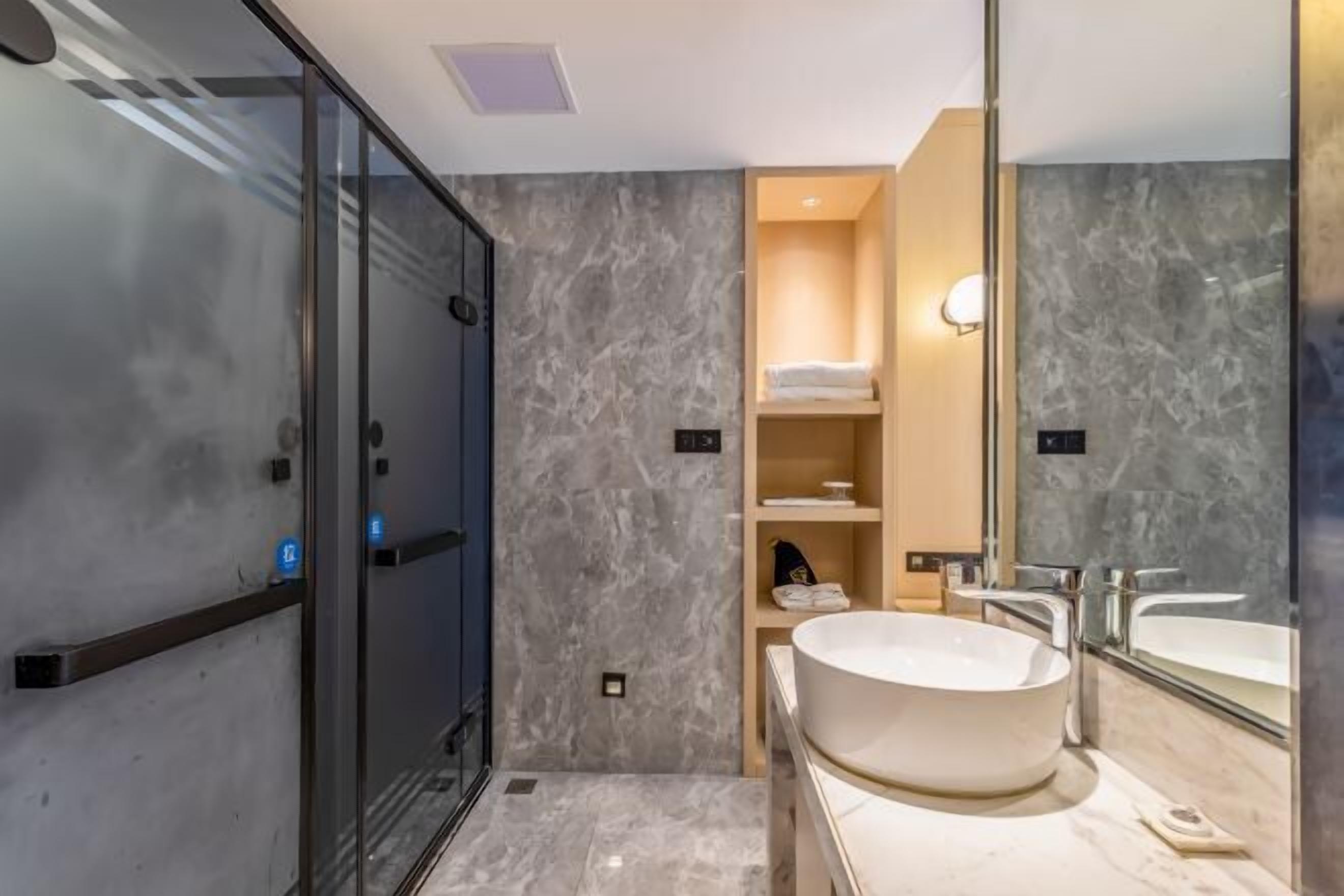 A modern bathroom with a glass shower enclosure, a freestanding bathtub, and a large mirror.