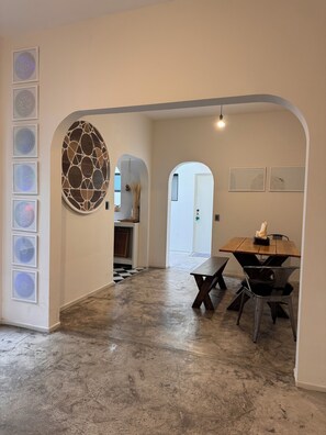 Experience a spacious, open-plan area with a polished floor, dining space, and unique mosaic wall piece.