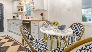 A modern kitchen with white cabinetry, a wooden countertop, and a dining area with a round table and patterned chairs. - 1 King and 1 Queen - Close to just about Everything (Fredericksburg)