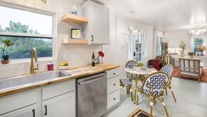 A modern kitchen with white cabinetry, a stainless steel dishwasher, and a wooden countertop. - 1 King and 1 Queen - Close to just about Everything (Fredericksburg)