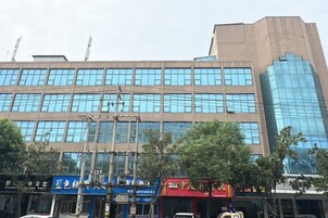 Un edificio de varios pisos con fachada de vidrio moderna, varias tiendas con rótulos y un cielo despejado.