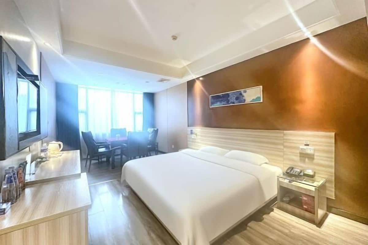 Una habitación de hotel con una cama, un escritorio con teléfono y una mesita de noche con lámpara.
