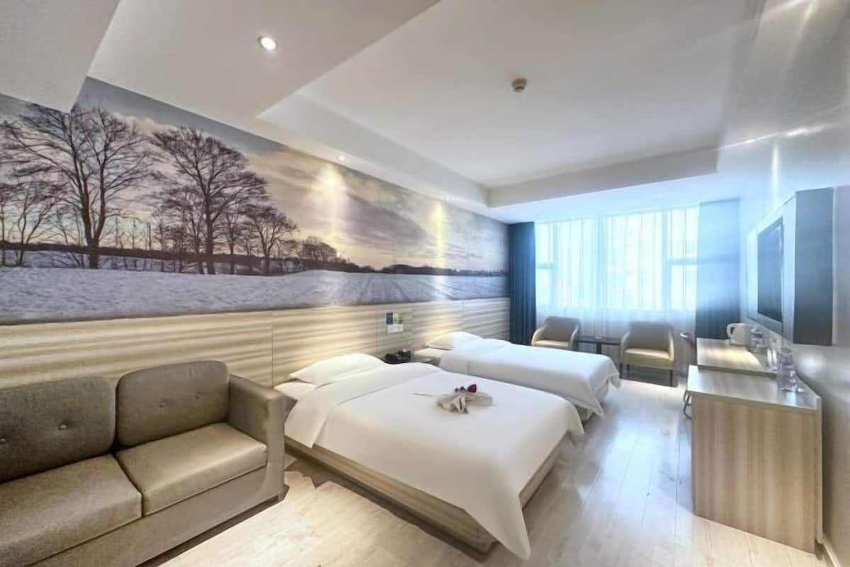 Una habitación de hotel con dos camas, un sofá, un escritorio y un ventanal grande.