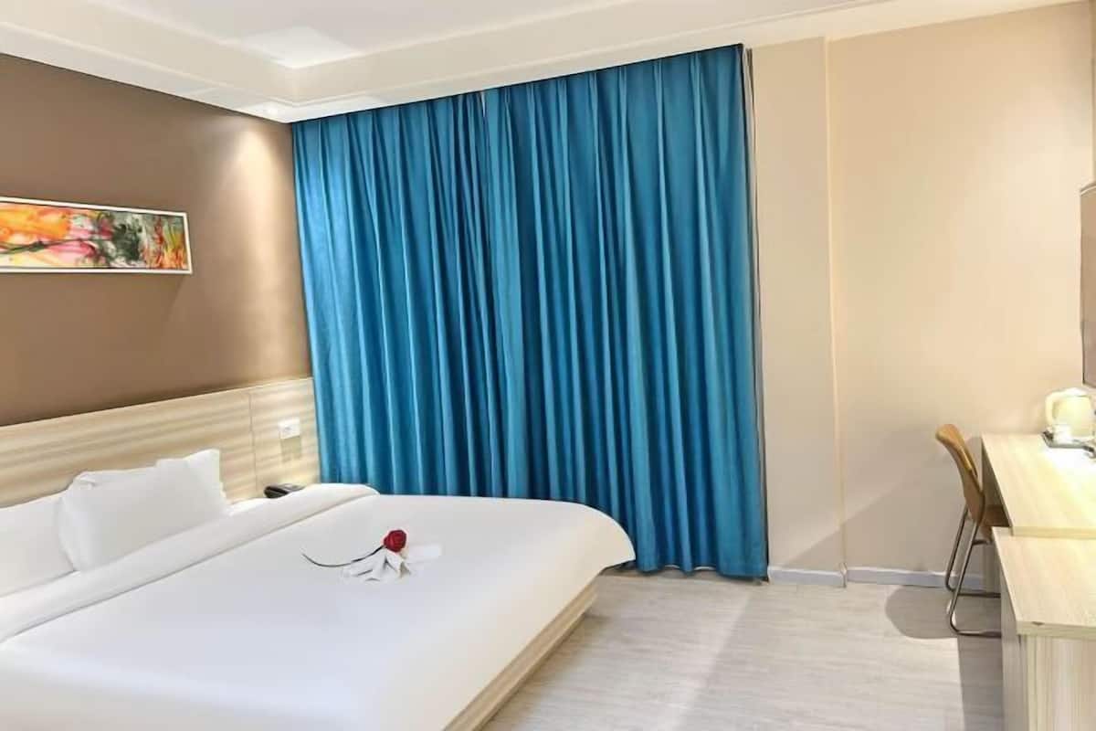 Habitación de hotel con cama, escritorio y un cuadro en la pared.
