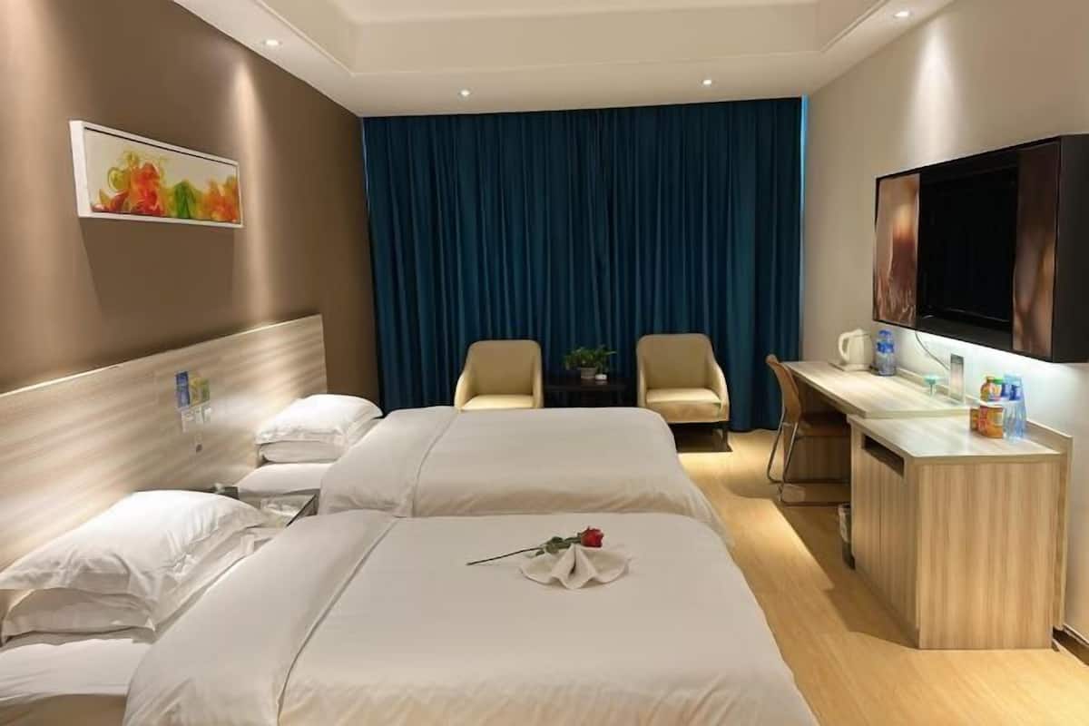 Habitación de hotel con dos camas, un escritorio, televisión y un amplio ventanal con cortinas.