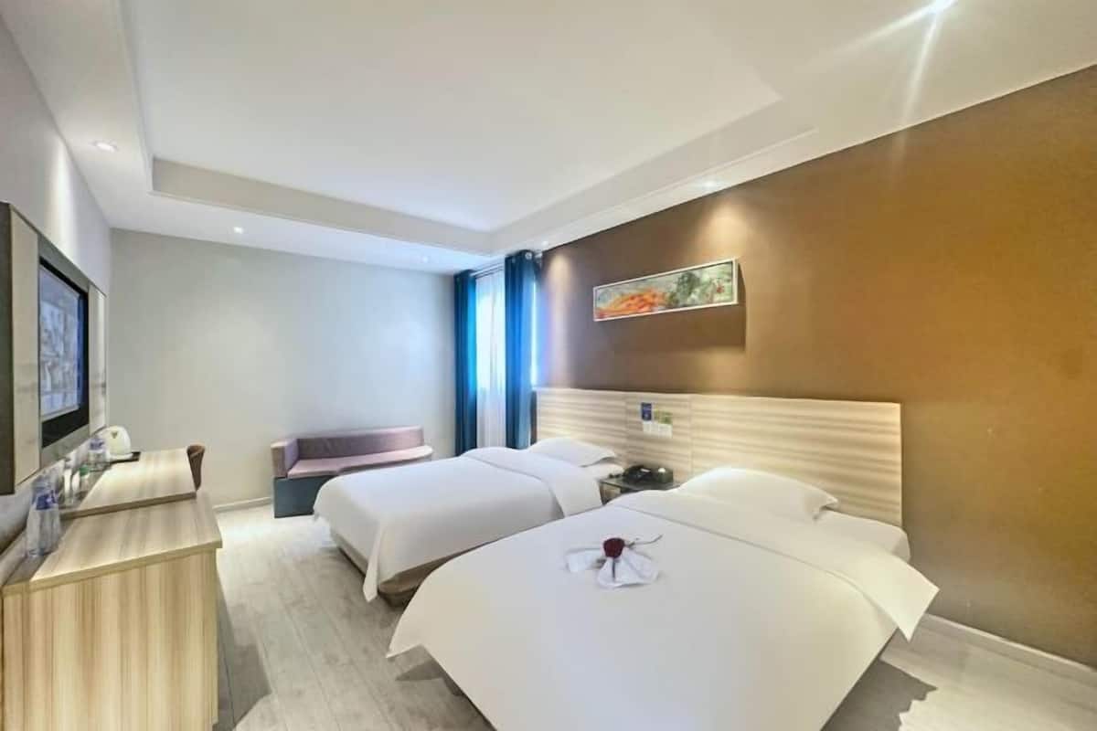 Una habitación de hotel con dos camas, un escritorio, un televisor y un cuadro en la pared.