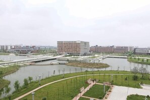 A riverside view with a modern building, a bridge, and a park area.