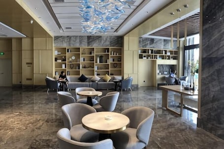 A lobby with marble flooring, seating areas, and a large bookshelf.. Boao Hotel